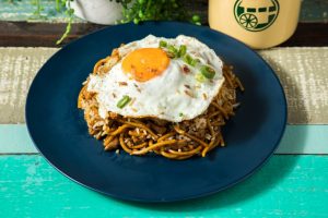 A mixture of rice and Hokkien noodle stir fry with Choice of Protein, fish cake (except Vegetable option), carrot, cabbage and bean sprouts cooked with homemade soy sauce and served with a sunny side egg