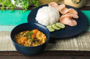 A curry dish boiled with yellow lentils, green peas, potatoes and carrot served with rice and prawn chips.